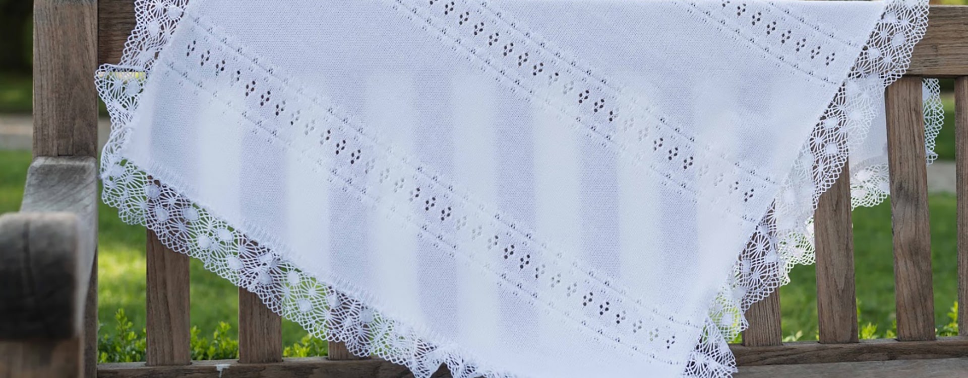 Couverture de baptême en maille ajourée bordée d'un large galon de dentelle de coton. Boutique Fil de Légende à Paris, Neuilly-sur-Seine.