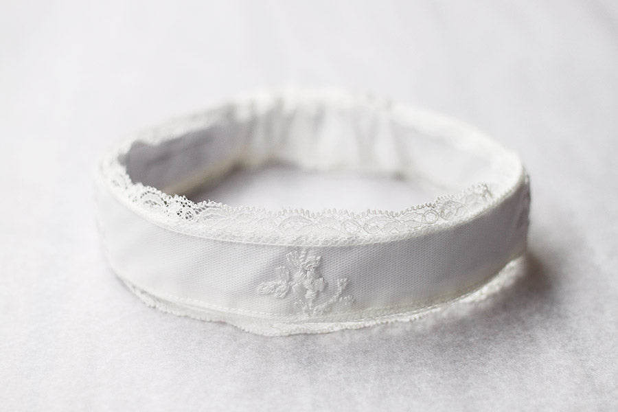 Bandeau cheveux cérémonie bébé fille en coton, tulle brodé et dentelle blanc cassé. A porter pour un baptême ou une cérémonie. Photo du gros plan du bandeau.