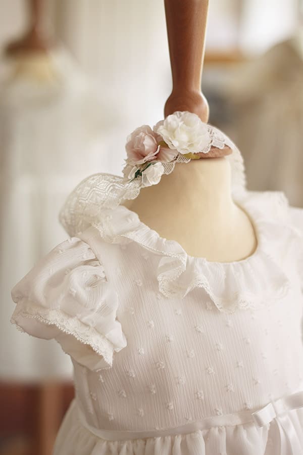 Bandeau cheveux bébé fille en dentelle blanc cassé avec fleurs blanches et roses. A porter pour un baptême ou une cérémonie. Photo du bandeau vu de côté.