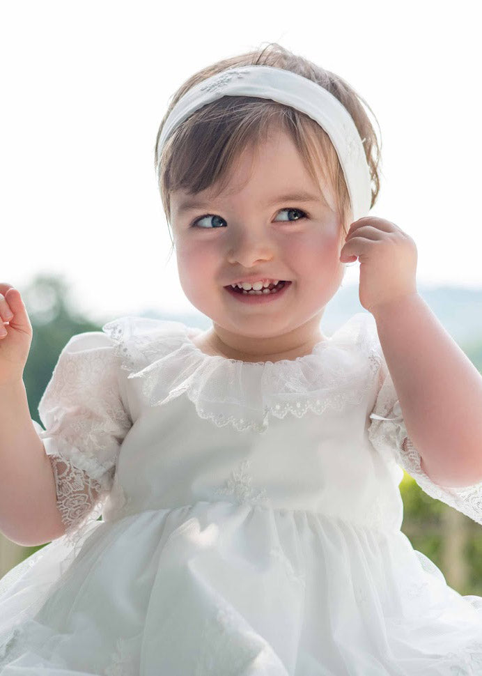 Bandeau cheveux cérémonie bébé fille en coton, tulle brodé et dentelle blanc cassé. A porter pour un baptême ou une cérémonie. Photo du bandeau porté.