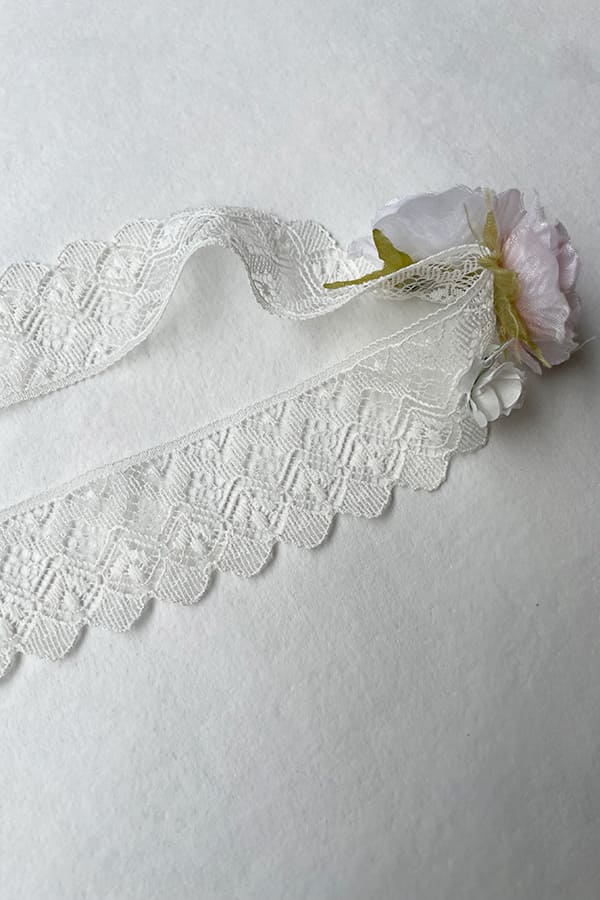 Bandeau cheveux bébé fille en dentelle blanc cassé avec fleurs blanches et roses. A porter pour un baptême ou une cérémonie. Photo du bandeau en dentelle.