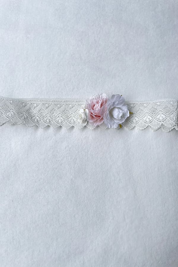Bandeau cheveux bébé fille en dentelle blanc cassé avec fleurs blanches et roses. A porter pour un baptême ou une cérémonie. Photo du bandeau posé à plat.