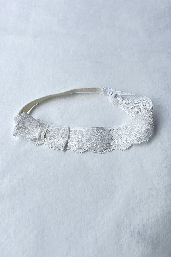 Bandeau cheveux bébé fille en dentelle blanc cassé avec nœud sur le côté. A porter pour un baptême ou une cérémonie. Boutique Fil de Légende à Paris, Neuilly-sur-Seine.