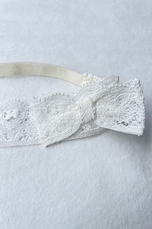 Bandeau cheveux bébé fille en dentelle blanc cassé avec nœud sur le côté. A porter pour un baptême ou une cérémonie. Photo du nœud en dentelle.