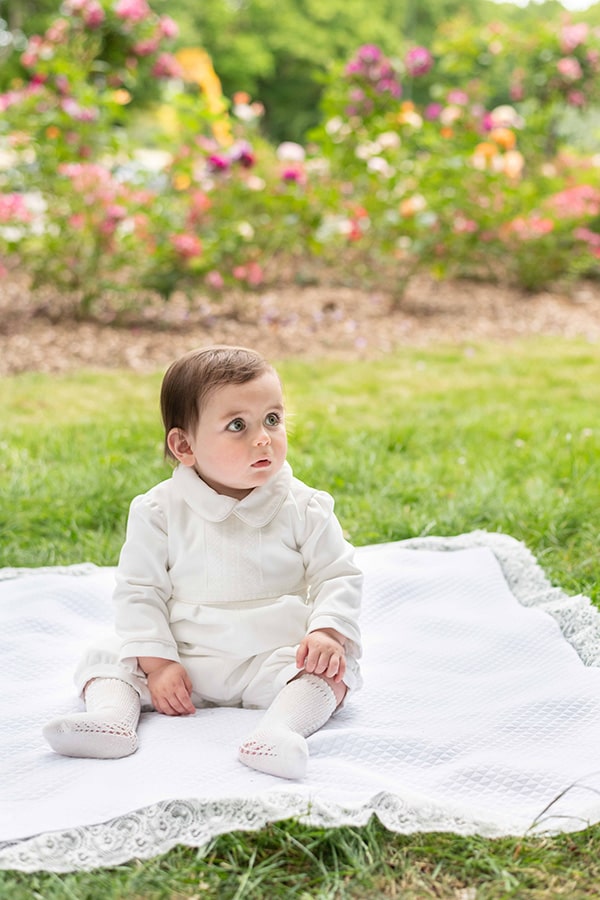 Barboteuse baptême d'hiver bébé garçon Baptiste en velours blanc cassé et dentelle de Calais. Doublure polaire. Création française Fil de Légende. Photo de la barboteuse portée vue de loin.