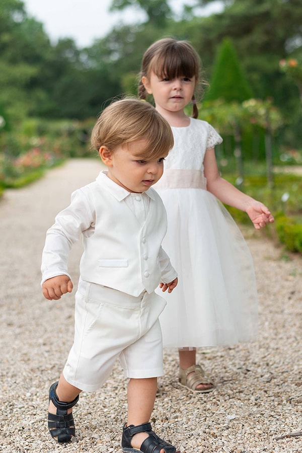 Bermuda cérémonie bébé garçon Oscar en coton blanc cassé. Création française Fil de Légende. Photo du bermuda porté avec la chemise et le gilet de cérémonie assortis vus de côté.
