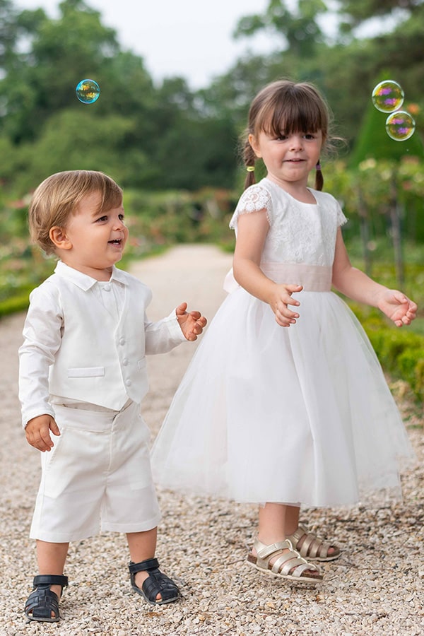 Bermuda cérémonie bébé garçon Oscar en coton blanc cassé. Création française Fil de Légende. Photo d'un bébé garçon avec le bermuda et d'une petite fille habillée en robe de cérémonie.