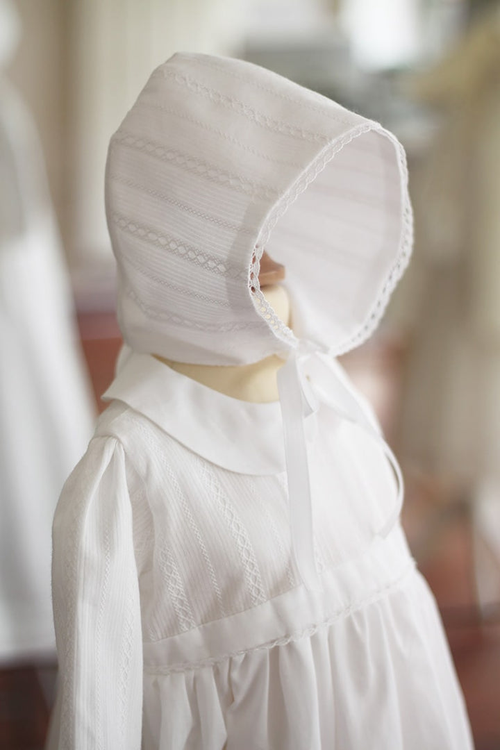 Bonnet baptême bébé mixte pour garçons et filles en coton brodé blanc. Modèle Andréa. Création française Fil de Légende. Photo du bonnet vu de côté.