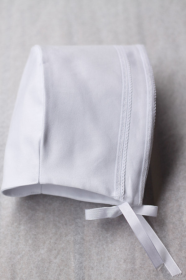 Bonnet de baptême bébé garçon Léo en coton blanc et galons de dentelle de coton. Création française Fil de Légende. Photo des détails de la dentelle.