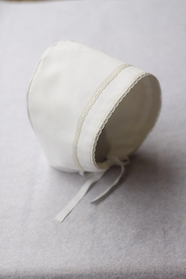Bonnet de baptême bébé garçon Oscar en coton blanc cassé et dentelle de coton ivoire. Création française Fil de Légende. Photo des détails de la dentelle.