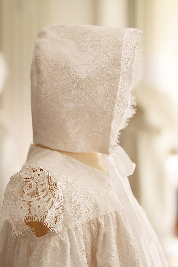 Bonnet de baptême bébé fille Amaia en dentelle italienne doublé coton. Création française Fil de Légende. Disponible en ligne et à la boutique Fil de Légende à Paris, Neuilly-sur-Seine.