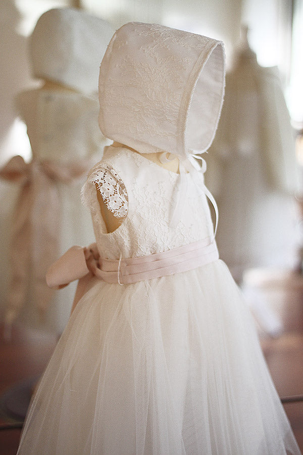 Bonnet de baptême bébé fille Aurélia en dentelle italienne blanc cassé doublé coton. Création française Fil de Légende. Disponible en ligne et à la boutique Fil de Légende à Paris, Neuilly-sur-Seine.