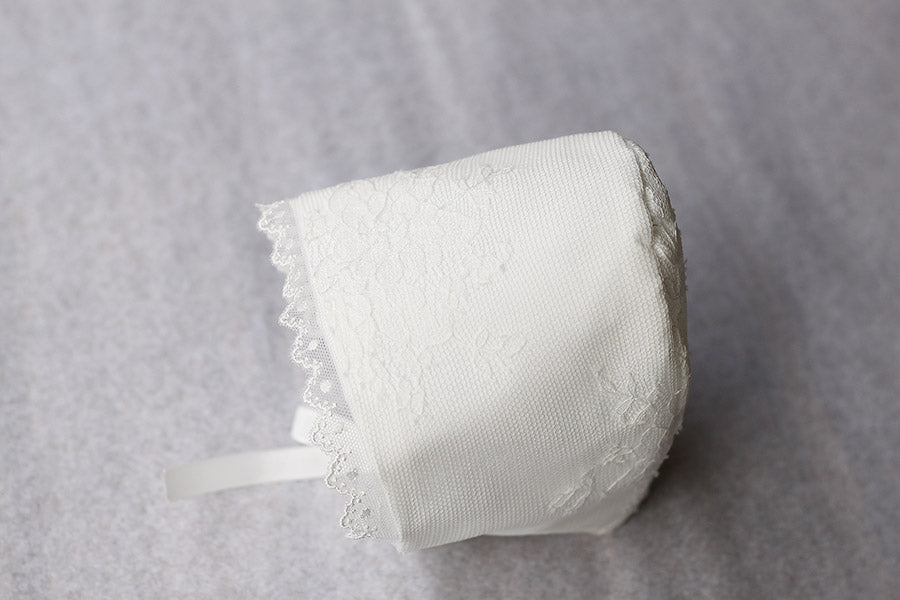 Bonnet de baptême traditionnel pour bébé en dentelle fine. Couleur blanc cassé. Fait main en France. Vue du dessus.