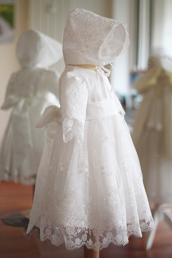 Bonnet de baptême bébé fille Estelle en tulle souple brodé doublé de satin blanc cassé. Création française Fil de Légende. Photo du bonnet porté avec la robe assortie.