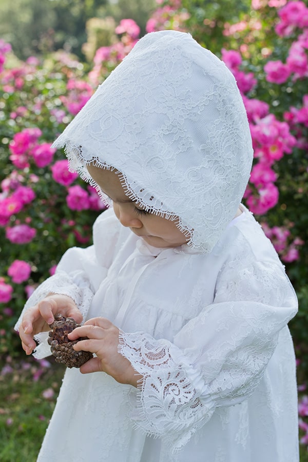 Bonnet de baptême bébé fille Amaia en dentelle italienne doublé coton. Création française Fil de Légende. Photo du bonnet porté par une petite fille.