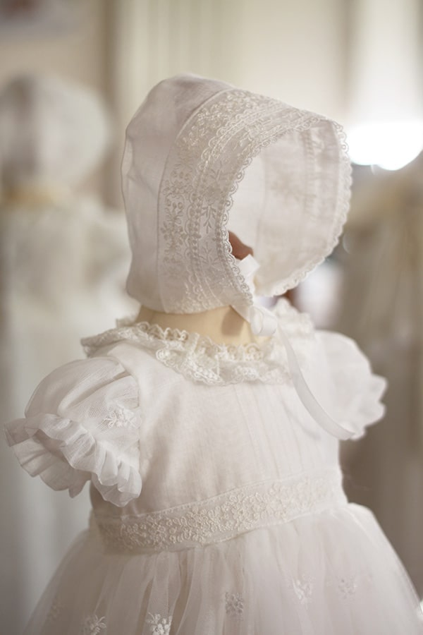 Bonnet de baptême bébé fille Gloria en mousseline et dentelle blanc cassé. Création française Fil de Légende. Photo du bonnet sur mannequin.