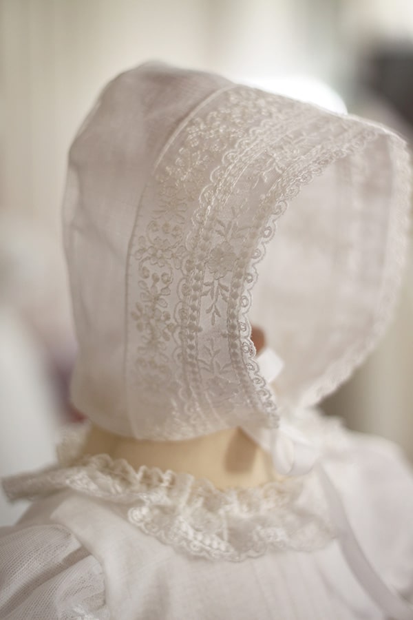 Bonnet de baptême bébé fille Gloria en mousseline et dentelle blanc cassé. Création française Fil de Légende. Photo de la dentelle du bonnet. 