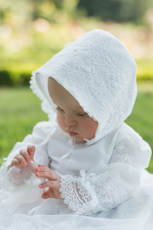 Bonnet de baptême bébé fille Sofia en tulle souple brodé italien blanc cassé, doublé de coton. Création française Fil de Légende. Photo du bonnet porté par une petite fille.