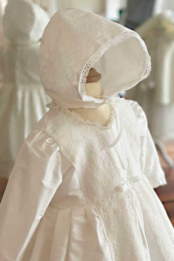 Bonnet de baptême pour bébé fille en soie et dentelle blanc cassé. Photo du bonnet vue de profile.