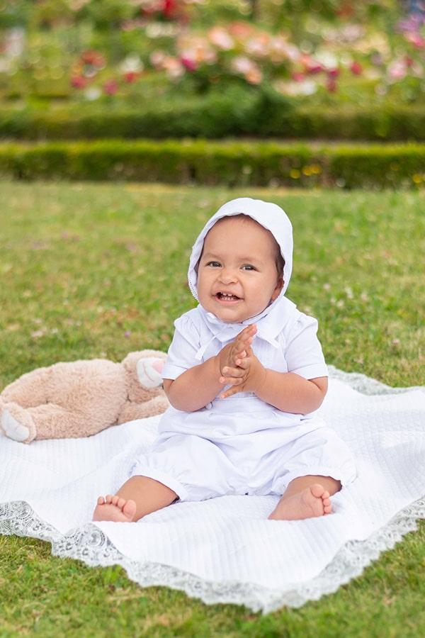 Bonnet de baptême bébé garçon Augustin en piqué de coton blanc et dentelle de coton. Création française Fil de Légende. Photo du bonnet porté par un bébé garçon.