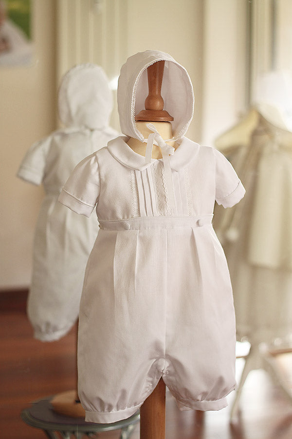Bonnet de baptême bébé garçon Augustin en piqué de coton blanc et dentelle de coton. Création française Fil de Légende. Photo du bonnet porté avec la barboteuse de baptême assortie.