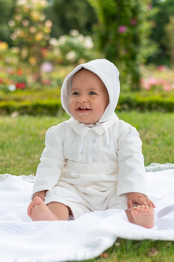 Bonnet baptême bébé garçon Paul pour l'hiver en velours de coton blanc cassé et galon de dentelle de coton. Création française Fil de Légende. Photo du bonnet porté par un bébé garçon.