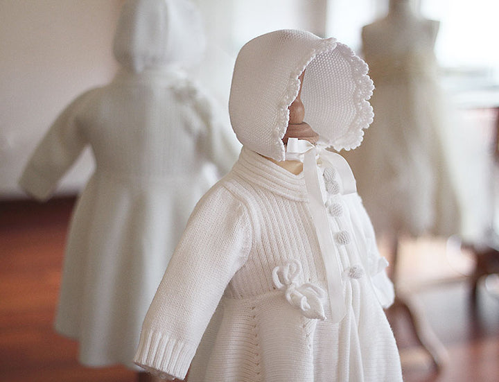 Bonnet de baptême Pauline tricoté en laine mélangée blanc cassé. Bordures de bonnet faites au crochet à la main. Création française Fil de Légende. Photo du bonnet vu de coté.