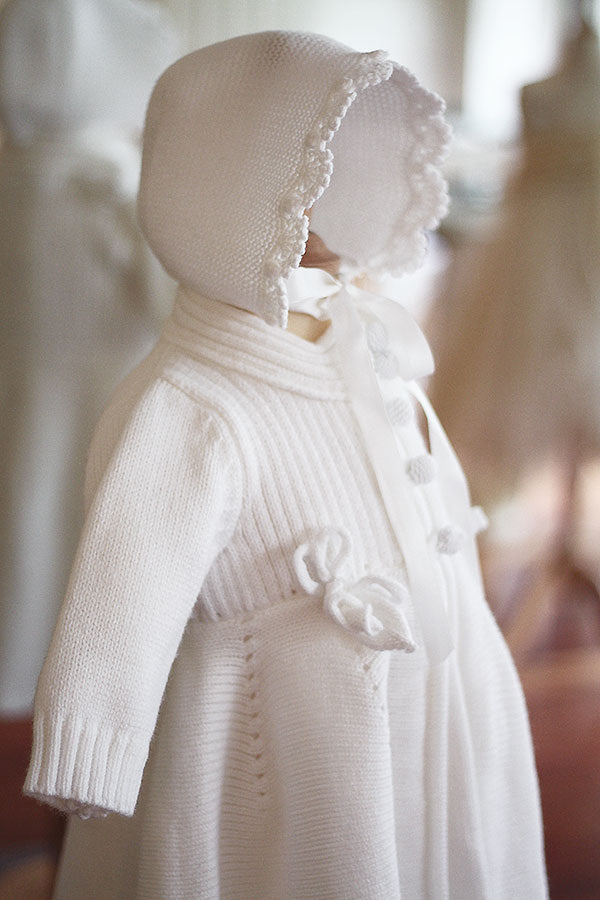 Bonnet de baptême Pauline tricoté en laine mélangée blanc cassé. Bordures de bonnet faites au crochet à la main. Création française Fil de Légende. Disponible en ligne ou en boutique à Paris, Neuilly-sur-Seine.