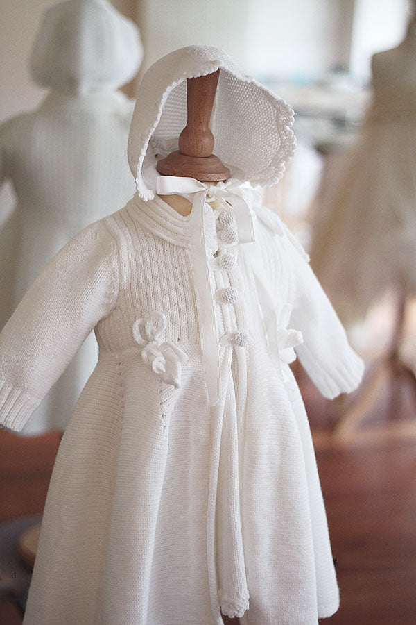Bonnet de baptême Pauline tricoté en laine mélangée blanc cassé. Bordures de bonnet faites au crochet à la main. Création française Fil de Légende. Photo du devant du bonnet.