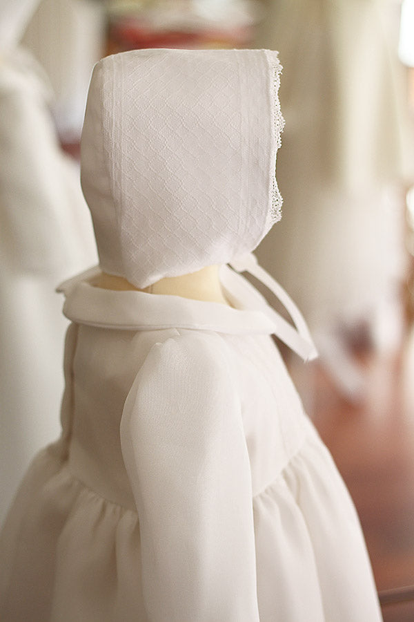 Bonnet de baptême bébé Victor en organza de soie blanc et dentelle blanche. Création française Fil de Légende. Disponible en ligne ou en boutique à Paris, Neuilly-sur-Seine.