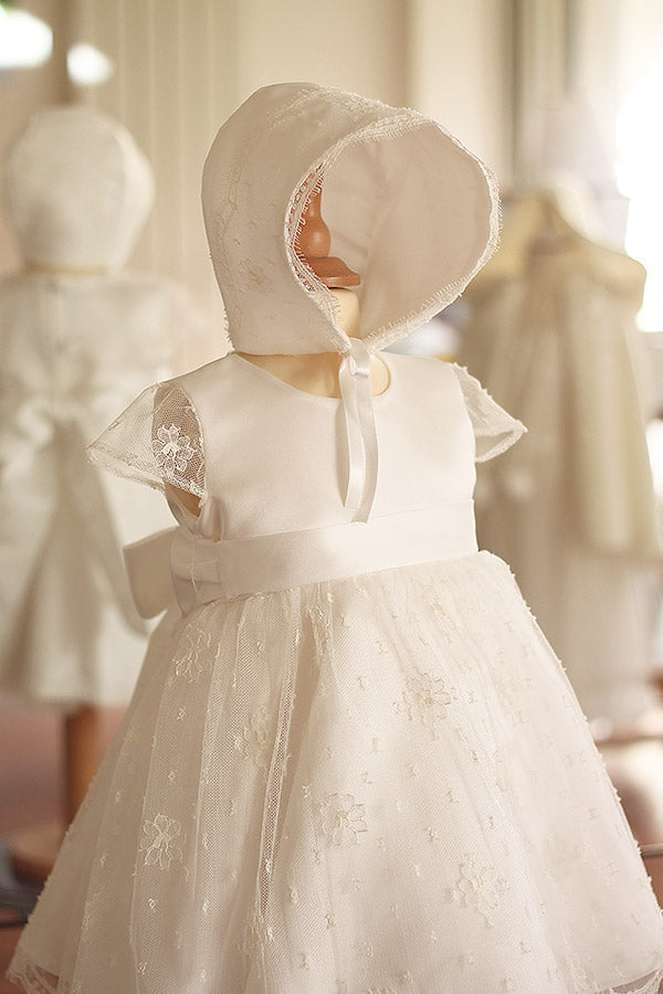 Bonnet de baptême bébé fille Maya en satin italien blanc cassé et dentelle française de calais Caudry. Création française Fil de Légende. Photo du bonnet avec la robe assortie.