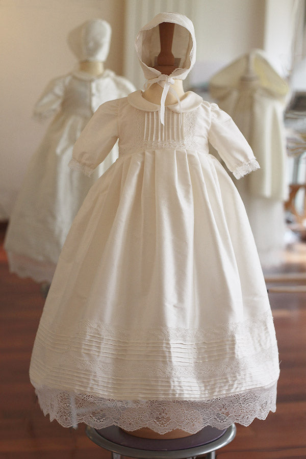 Bonnet de baptême et brit milah en soie et dentelle blanc cassé. Photo du bonnet vu de face avec la robe de baptême en soie assortie.
