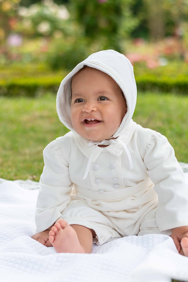 Bonnet baptême bébé garçon Paul pour l'hiver en velours de coton blanc cassé et galon de dentelle de coton. Création française Fil de Légende. Photo du bonnet porté par un bébé garçon vu de près.