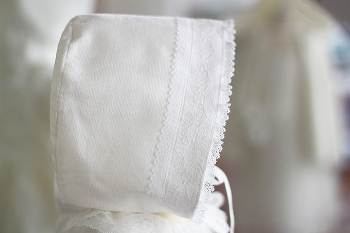 Bonnet de baptême bébé fille Angelina. Bonnet pour l'hiver en velours de coton et dentelle de Calais, doublé polaire. Création française Fil de Légende. Photo de la bordure du bonnet.