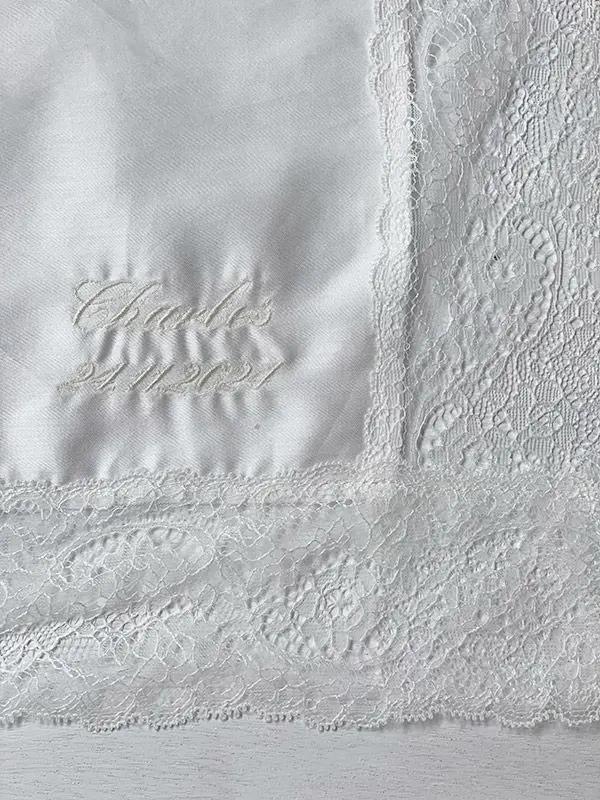 Broderies baptême prénom et date du baptême en fil blanc cassé sur une serviette de baptême. Boutique Fil de Légende à Paris, Neuilly-sur-Seine.