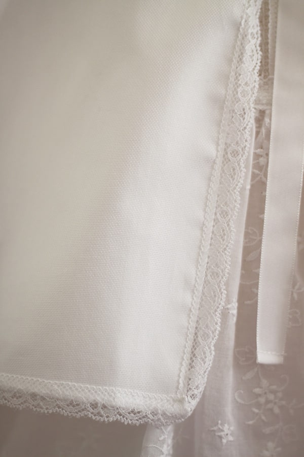 Cape de baptême bébé fille en coton blanc et galon de dentelle. Création française Fil de Légende. Photo du ruban.