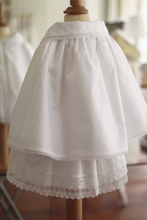 Cape de baptême bébé fille en coton blanc et galon de dentelle. Création française Fil de Légende. Photo de la cape vue de dos.