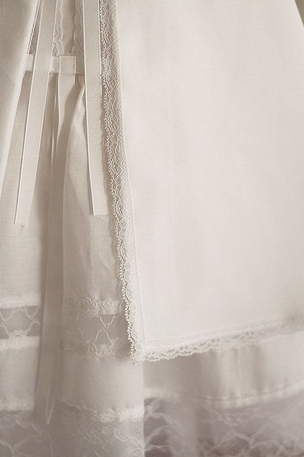 Cape de baptême bébé fille en coton blanc et galon de dentelle. Création française Fil de Légende. Photo du galon de dentelle bordant la cape.