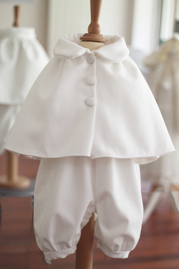 Cape de baptême automne hiver pour fille ou garçon en Mouflon blanc cassé doublé polaire. Fermeture avec boutons. Création française Fil de Légende. Disponible en ligne ou en boutique à Paris, Neuilly-sur-Seine.  