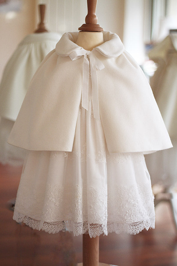 Cape de baptême fille pour l'automne hiver en lainage blanc cassé doublée polaire. Création française Fil de Légende. Disponible en ligne ou en boutique à Paris, Neuilly-sur-Seine. 