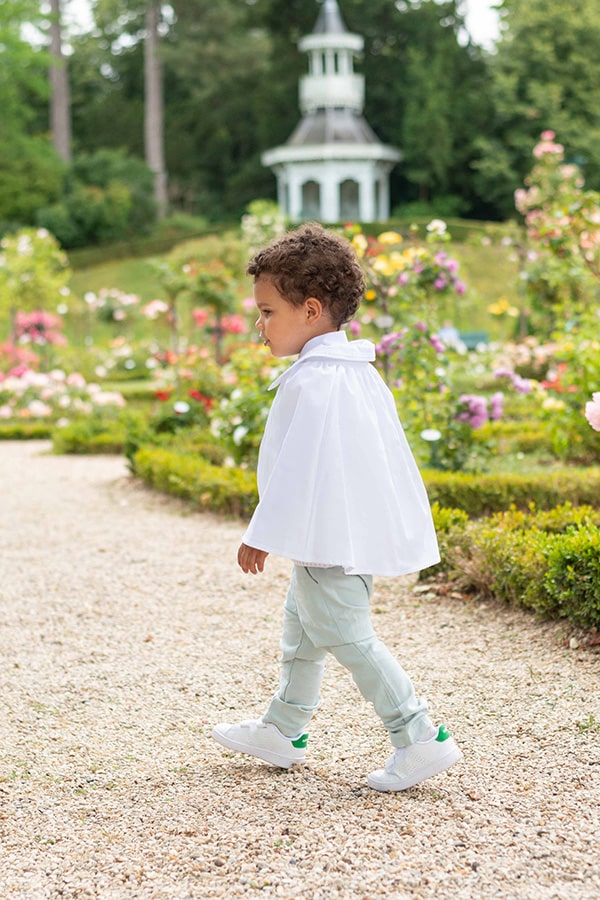 Cape de baptême bébé garçon Adrien en coton blanc et dentelle de coton.  Création française Fil de Légende. Photo de la cape portée par un enfant qui marche.