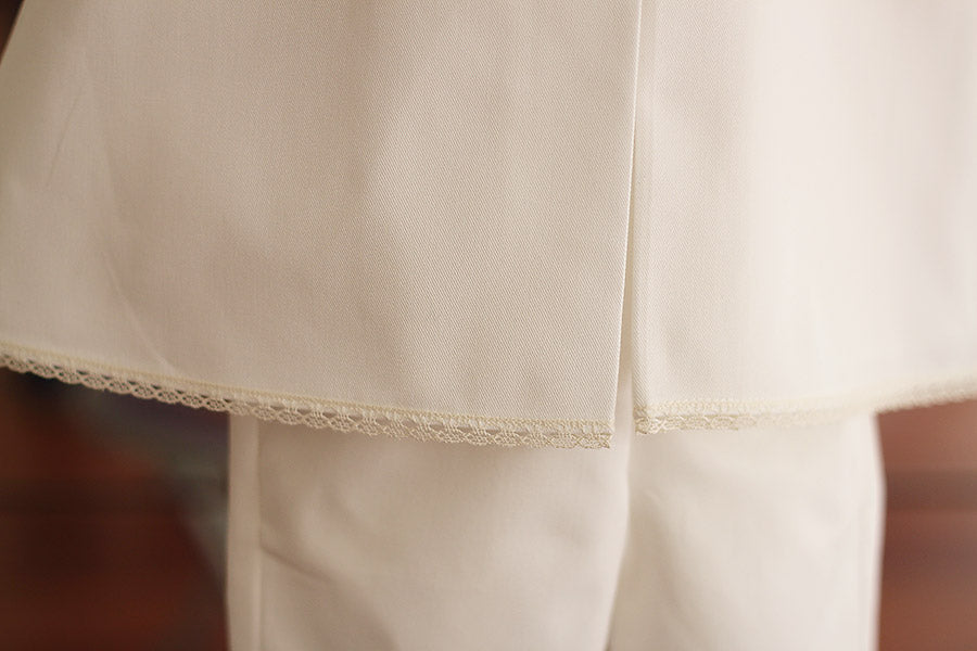 Cape de baptême bébé garçon Oscar en coton blanc cassé et galons de dentelle de coton. Création française Fil de Légende. Photo du bas de la cape avec le galon de dentelle.