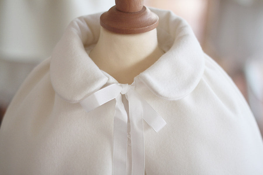 Cape de baptême fille pour l'automne hiver en lainage blanc cassé doublée polaire. Création française Fil de Légende. Photo du col. 