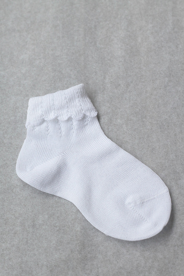 Chaussettes bébé fille en coton blanc avec un revers dentelé. Parfaites pour êtres portées avec une robe blanche de cérémonie pour bébé ou une robe de baptême.