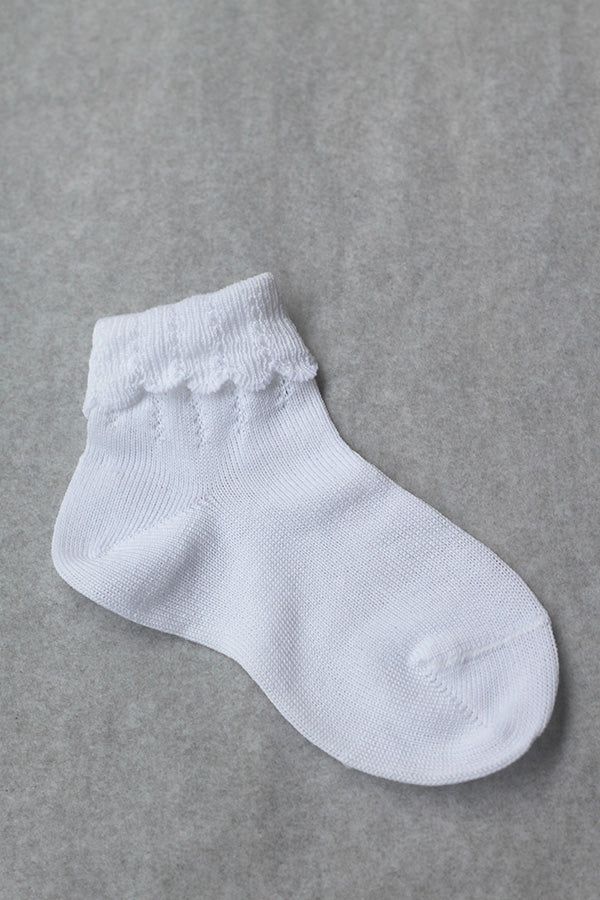 Chaussettes bébé fille en coton blanc avec un revers dentelé. Parfaites pour êtres portées avec une robe blanche de cérémonie pour bébé ou une robe de baptême.