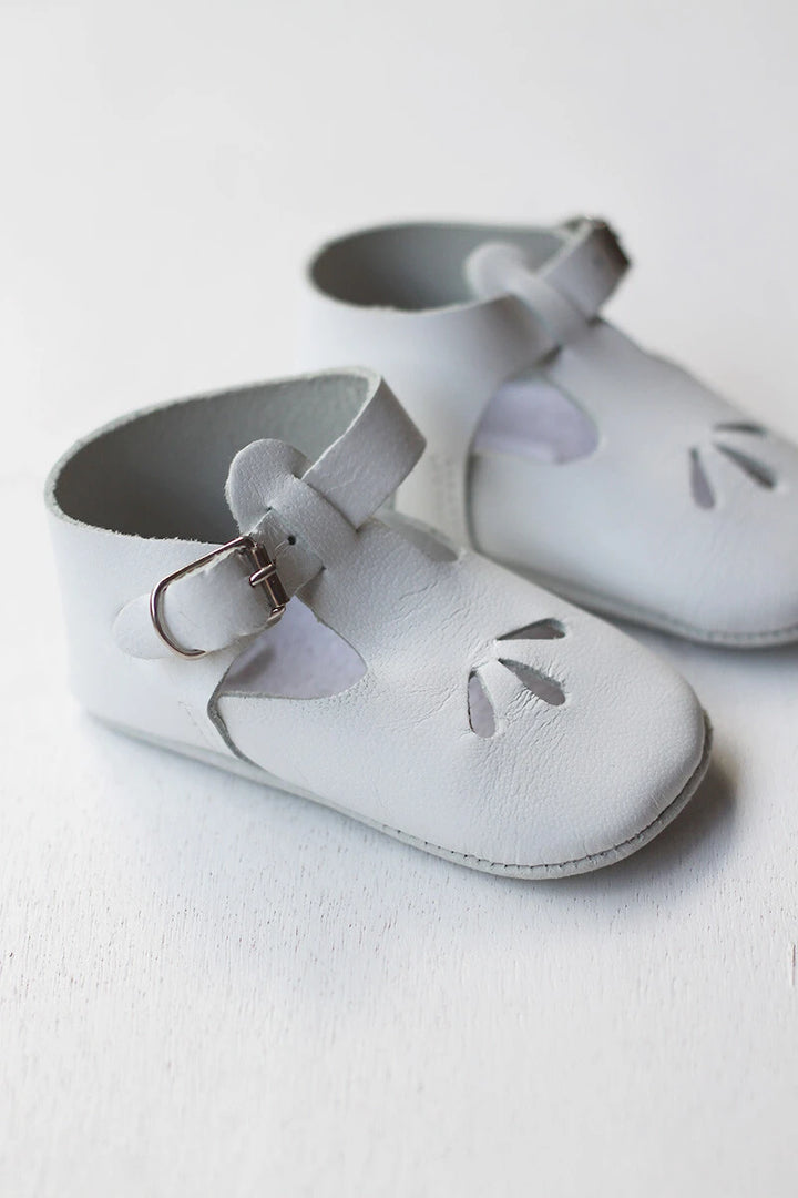 Chaussons cérémonie baptême bébé en cuir blanc. Idéal pour la saison printemps/ été. Ouverture à boucle. Vue de côté.
