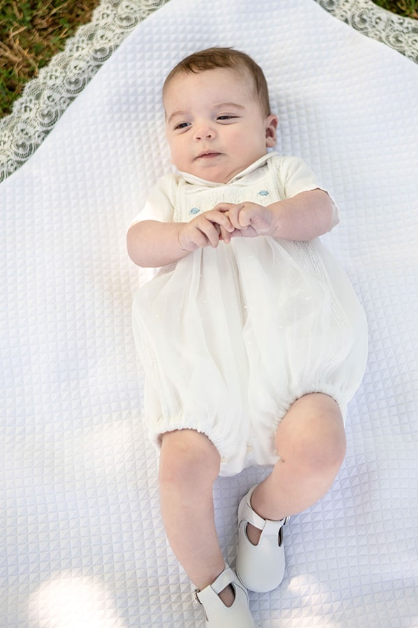 Chaussons baptême cérémonie bébé fille ou garçon pour l'été. Chaussons en cuir blanc avec une ouverture à boucle. Photo des chaussons portés sur bébé.