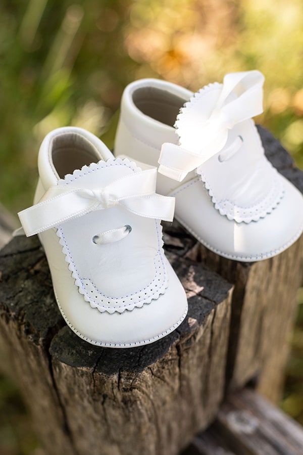 Chaussons montants bébé fille pour  cérémonie ou baptême - en cuir blanc cassé avec une décoration raffinée et un joli nœud en satin - vue de coté à l'extérieur