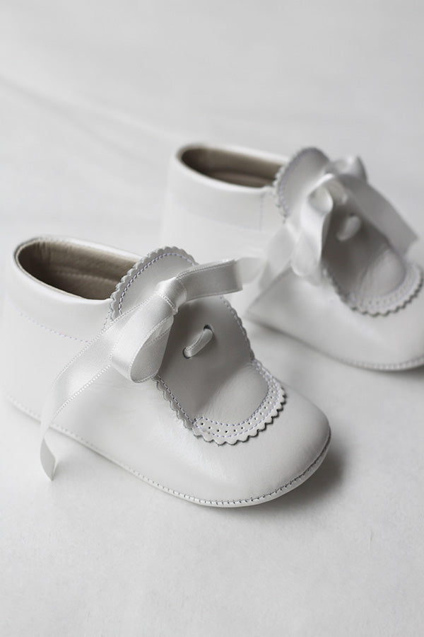 Chaussons montants bébé fille pour  cérémonie ou baptême - en cuir blanc cassé avec une décoration raffinée et un joli nœud en satin -  Vue de coté