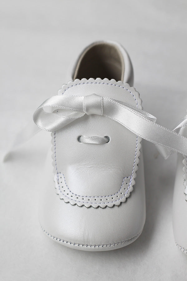 Chaussons montants bébé fille pour  cérémonie ou baptême - en cuir blanc cassé avec une décoration raffinée et un joli nœud en satin -  Vue d'un des chaussons.